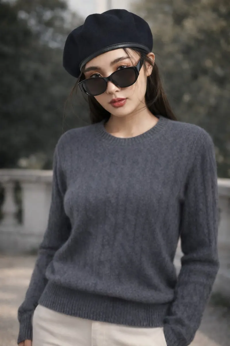 Woman wearing a black beret and sunglasses with a charcoal grey knit sweater and light trousers in an outdoor setting
