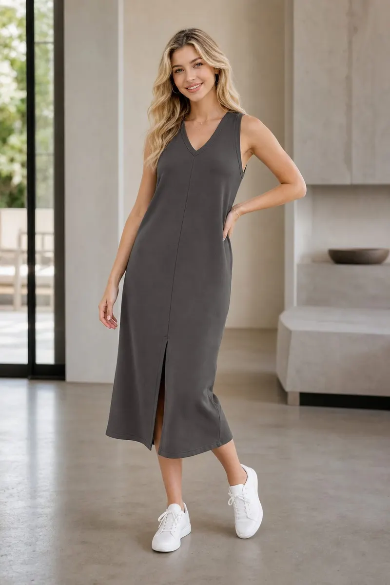 Blonde woman wearing a charcoal sleeveless midi dress with white sneakers in a modern minimalist indoor setting
